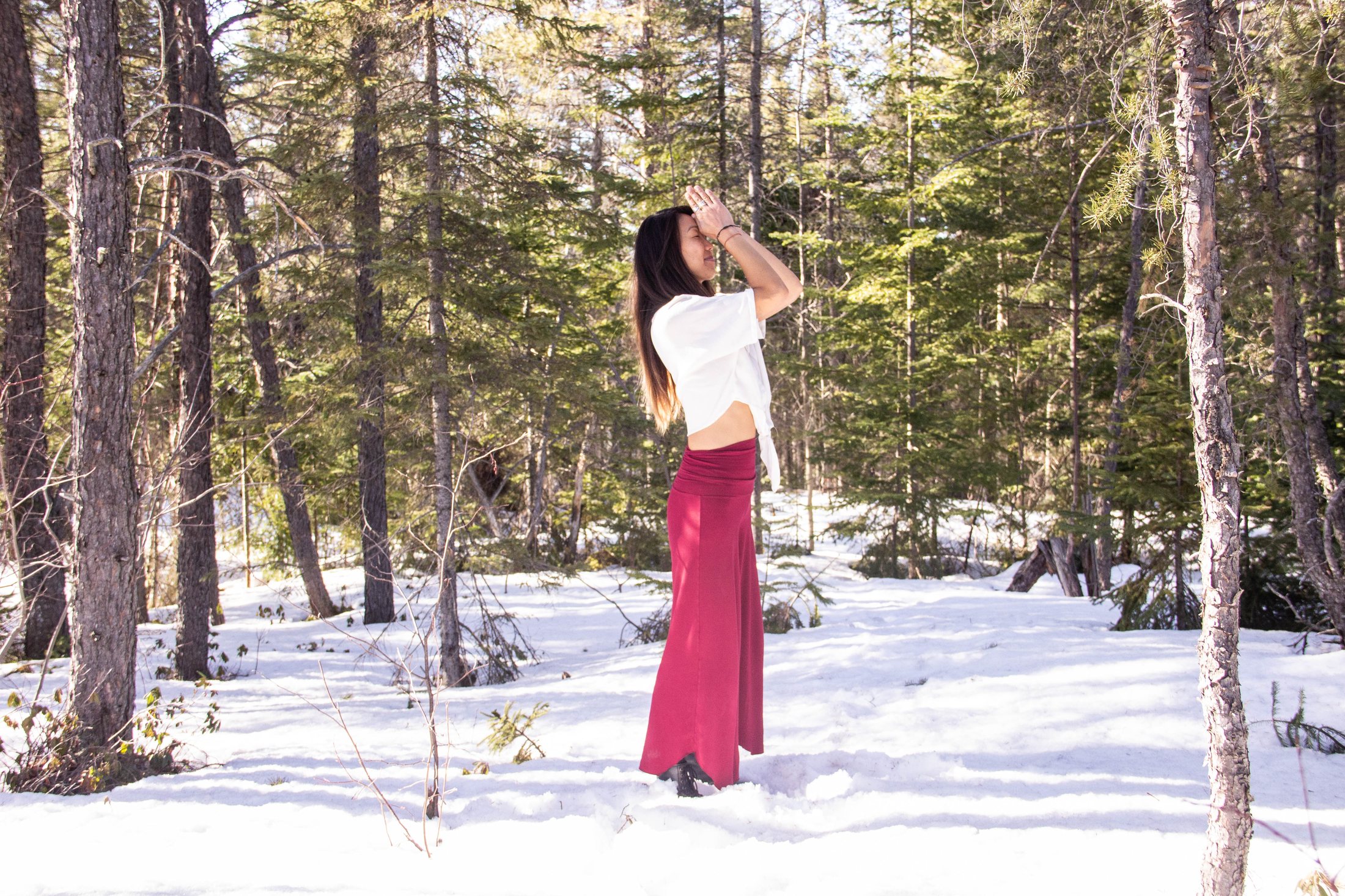 Letitia Rose debout dans une forêt enneigée, reliée à la nature et au territoire.