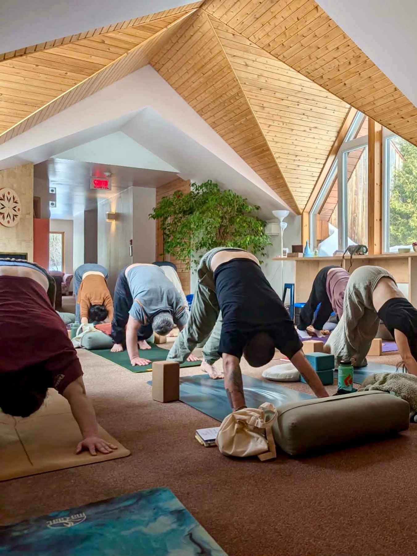 Groupe en pratique de yoga dans un espace de retraite lumineux avec structure de bois.