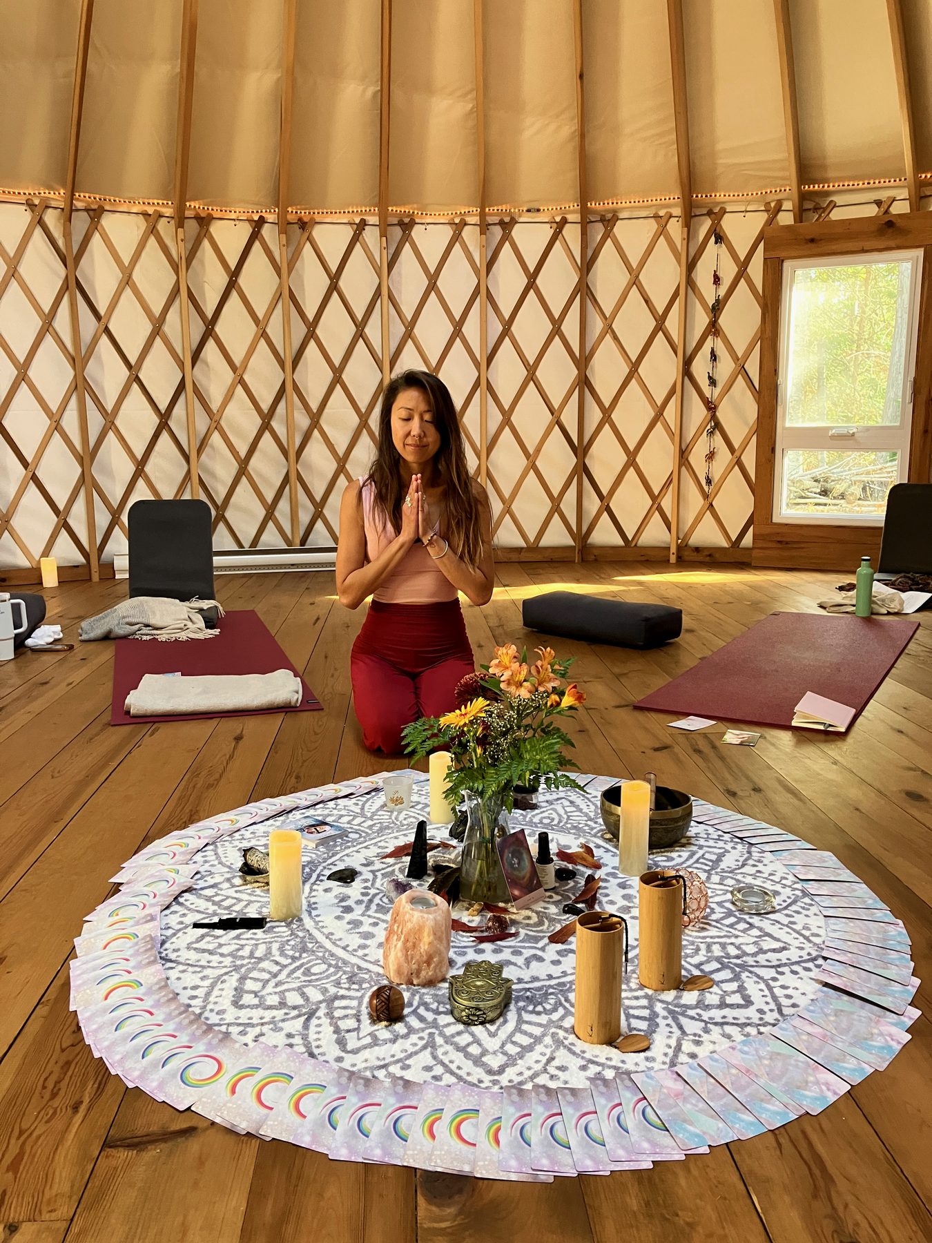 Espace de retraite avec cercle rituel, fleurs, bougies et tapis de yoga.