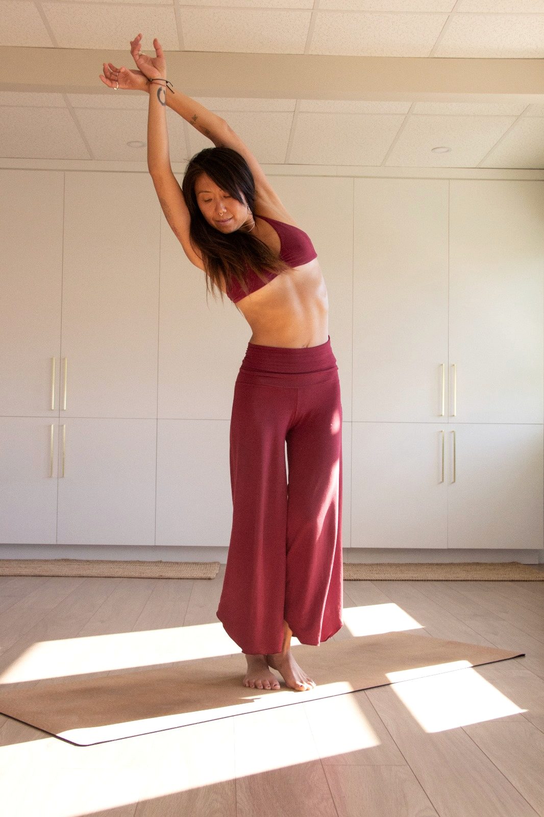 Letitia Rose en mouvement debout sur un tapis dans un studio clair.