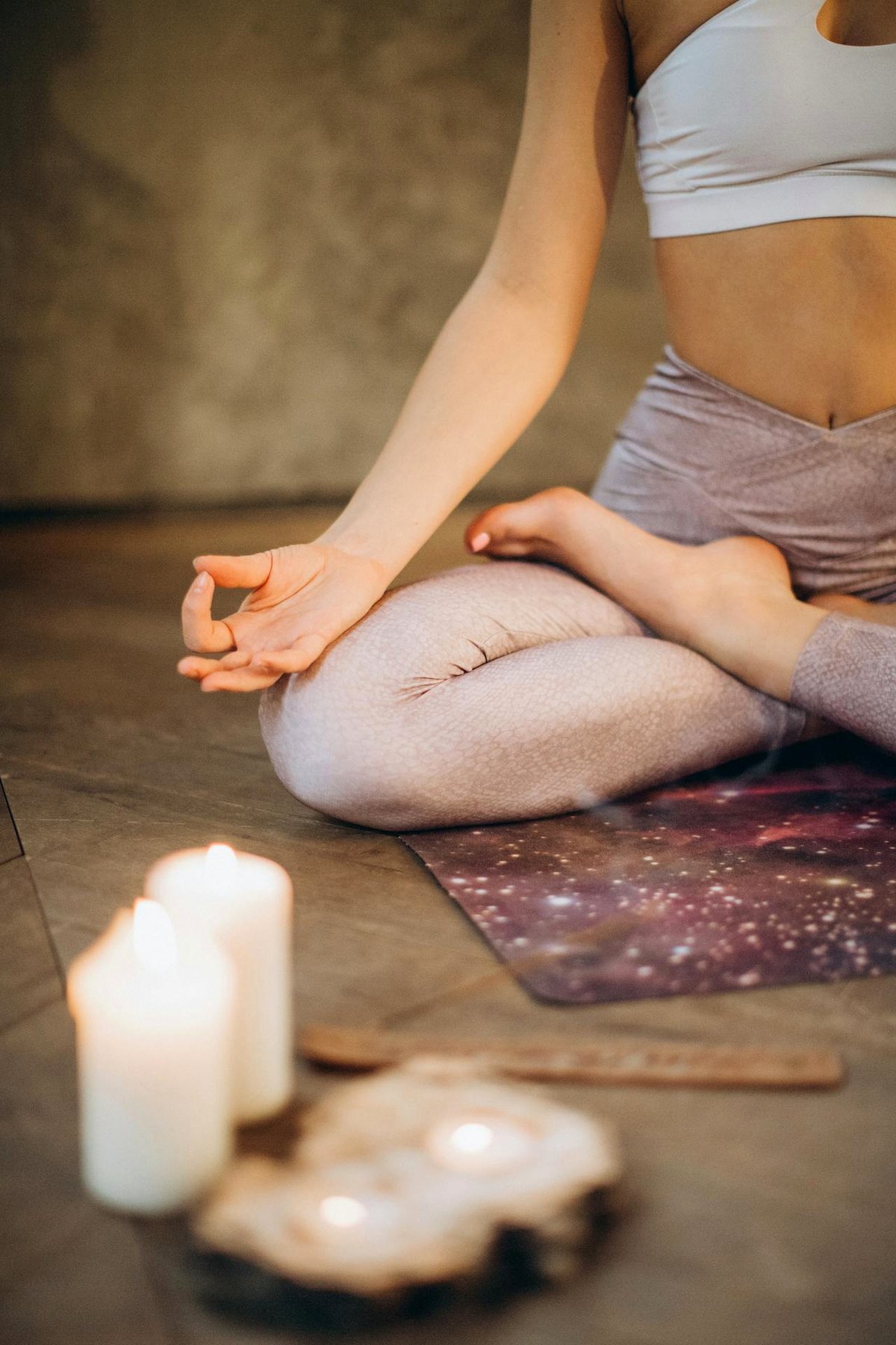 Personne assise en méditation avec bougie et lumière douce.