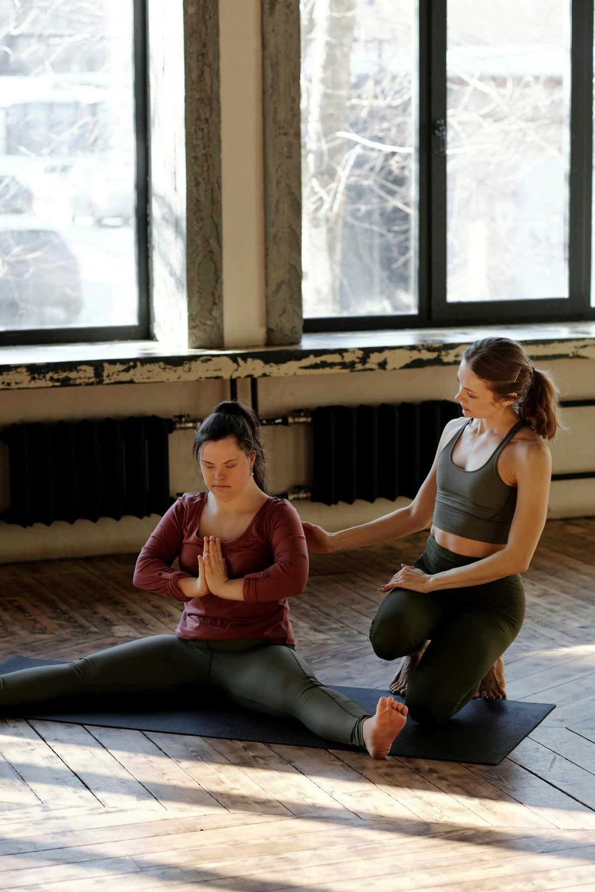 Deux personnes dans une pratique de yoga accompagnée dans un studio lumineux.