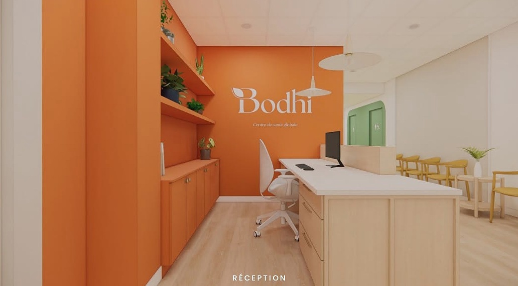 Réception du Centre Bodhi avec mur orangé, comptoir clair et logo Bodhi.